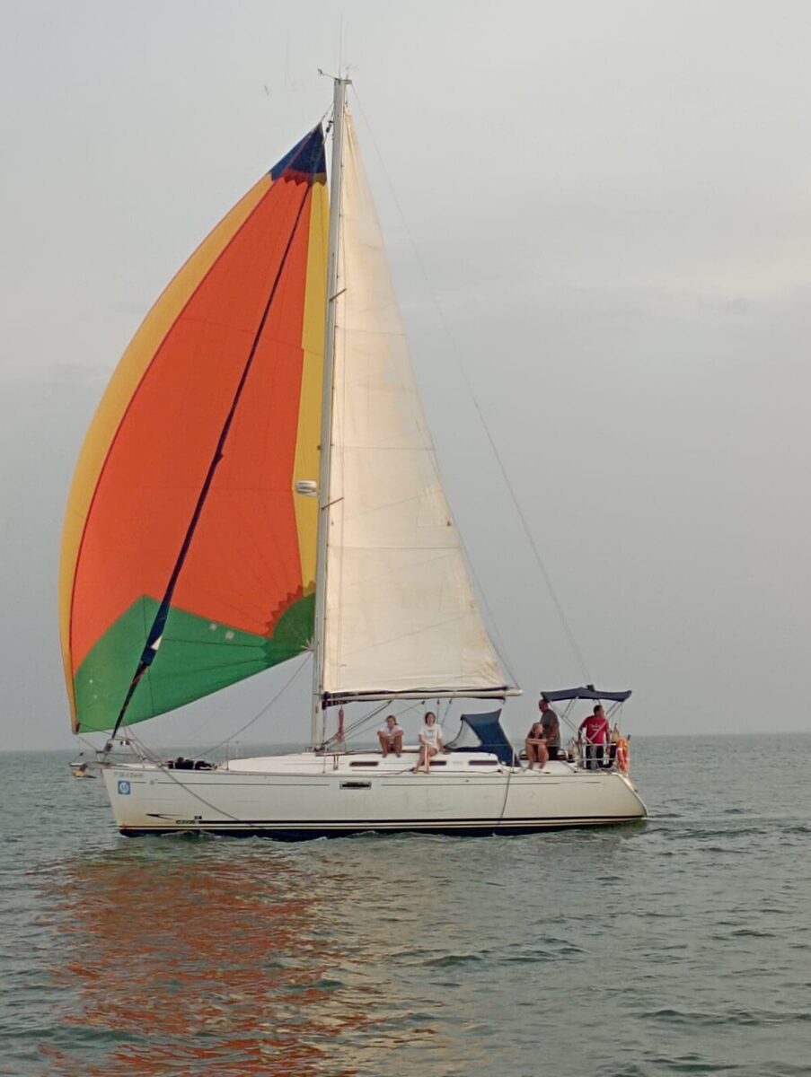 Velero con spinnaker multicolor durante la manga de vuelta de la Travesía de Doñana hacia Mazagón